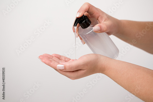 Close up of woman hand using alcohol gel for cleaning and sanitize. Gel pump dispenser on white background. Prevent the spread of germs and avoid infection from corona virus