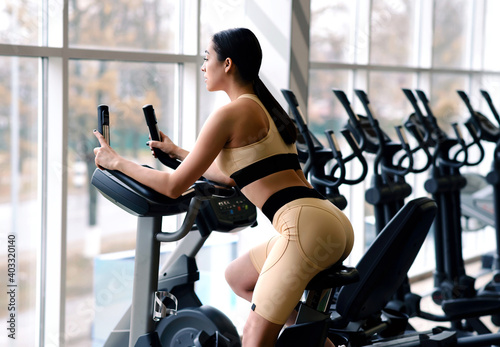 Slim athlete woman doing fitness exercises on a bike in the gym. Healthy lifestyle motivation