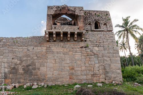 Hampi, Karnataka, India - November 4, 2013: Closeup of Gray-brown stone Mohammadan Watch tower in its setting under blue sunset sky and green palm trees, bushes and grass.  photo