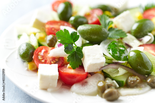 Healthy Salad with Feta Cheese, Green Olives, Baby Spinach, Cucumber, Cherry Tomatoes and Capers. Bright background. Close up. 