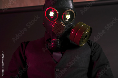 cosplay of a guy in a gas mask with a red light on a dark background with glowing eyes © madnessbrains