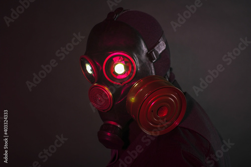 cosplay of a guy in a gas mask with a red light on a dark background with glowing eyes © madnessbrains