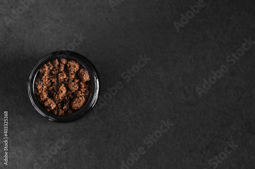 Dark muscovado sugar in a jar on black table with copy space. Top view. photo