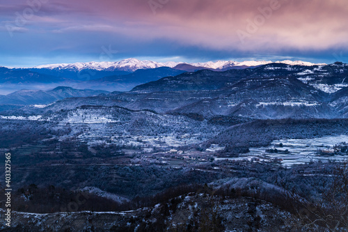 Snowy winter mountainous landscape on a cold sunrise. Icy landscape with hoarfrost. Mountain range of Bellmunt, Osona, Catalonia, Spain with Pyrenees at background.