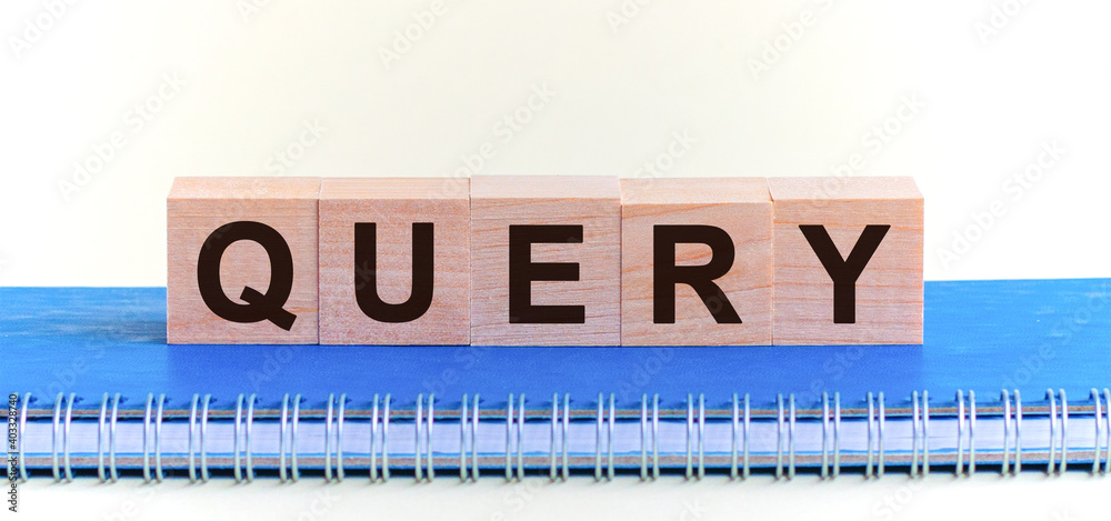Query - a word made of wooden blocks with black letters, a row of blocks is located on a grey notepad