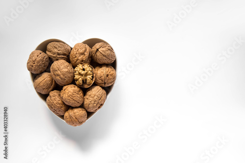 Wallpaper Mural Whole walnuts and one cracked broken heart in a white heart-shaped bowl on a white background. Top view. Place for text. Torontodigital.ca