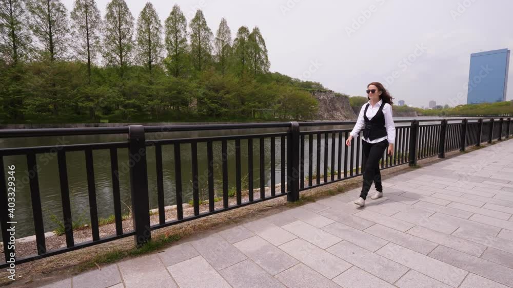Business lady walk at embankment of Osaka Castle outer moat. European woman have free time during duty trip to Japan, take quick look at city landmarks Business lady walk at embankment of Osaka Castle outer moat. European woman have free time during duty trip to Japan, take quick look at city landmarks
