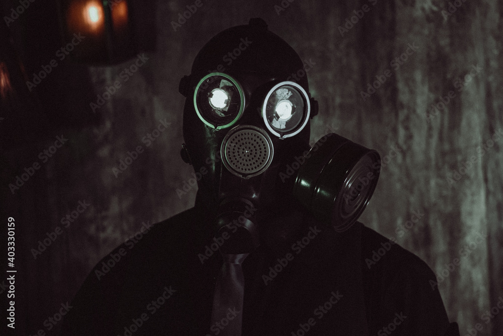 cosplay of a guy in a gas mask with a red light on dark background with glowing eyes Stock Photo |