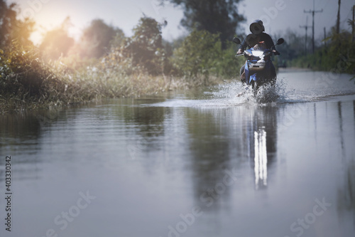 Motorcycle run through flood water after hard rain with water spray from the wheels .Stop action ( capture with the high speed shutter) and selective focus.