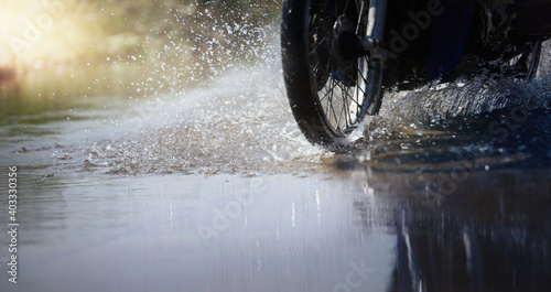 Motorcycle run through flood water after hard rain with water spray from the wheels .Stop action ( capture with the high speed shutter) and selective focus. © chokchaipoo