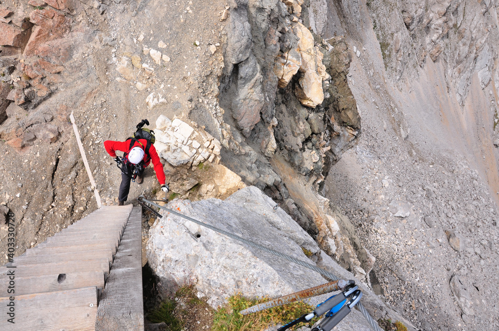 Człowiek w białym kasku stoi pod drabiną na via ferracie, Dolomity, Włochy
