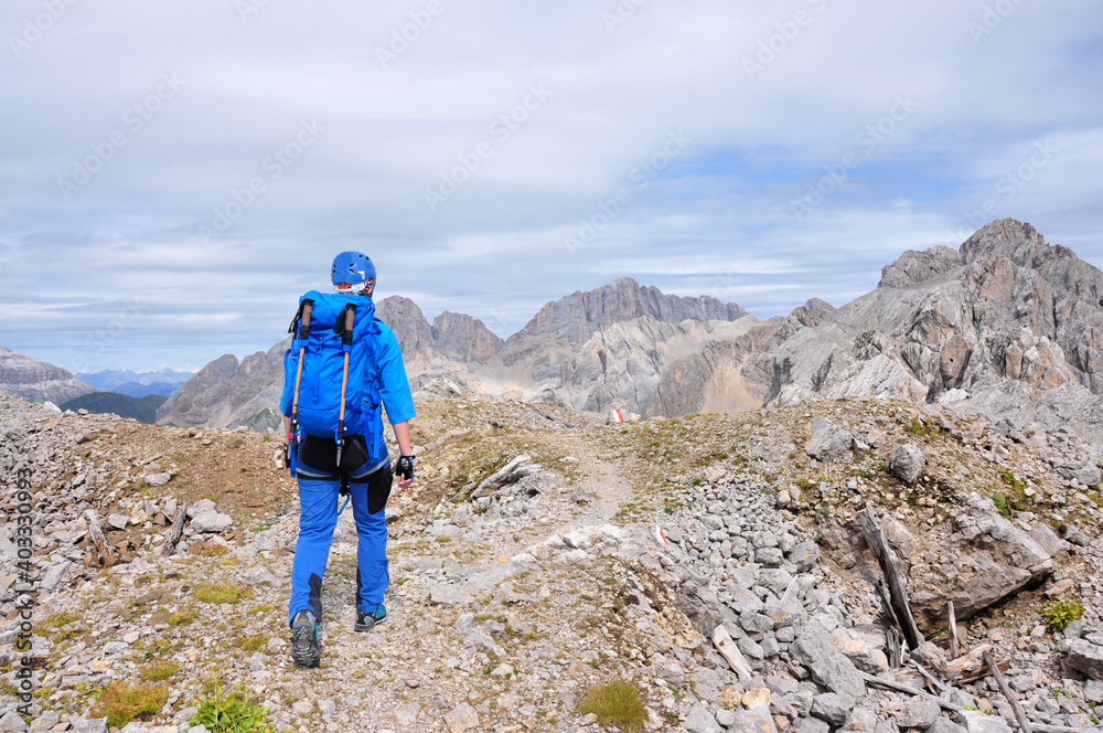 Kobieta ubrana na niebiesko idzie szlakiem w Dolomitach