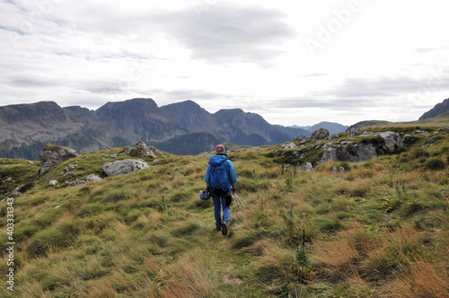 Kobieta w niebieskim stroju idzie górską łąką, Dolomity, Włochy