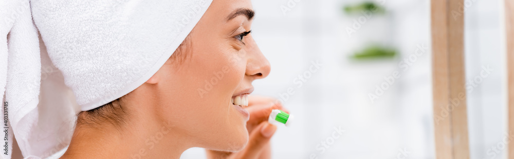 side view of woman with white towel on head holding toothbrush in bathroom, banner side view of woman with white towel on head holding toothbrush in bathroom, banner