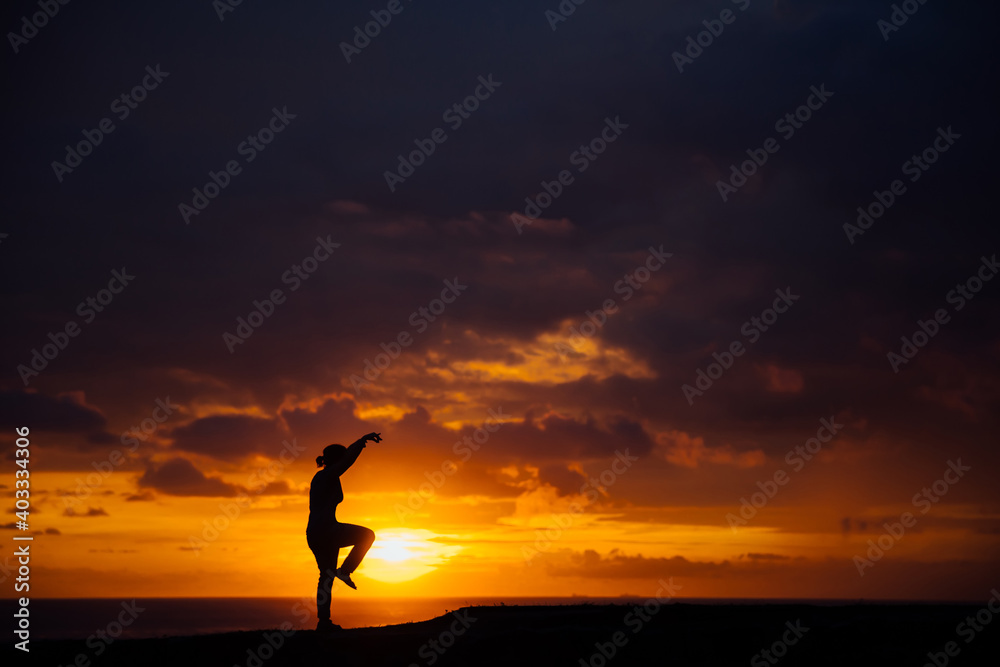 Silhouette of woman practicing karate at sunset
