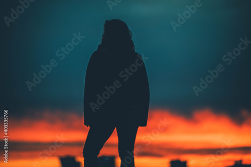 A woman looks down at the city at sunset

