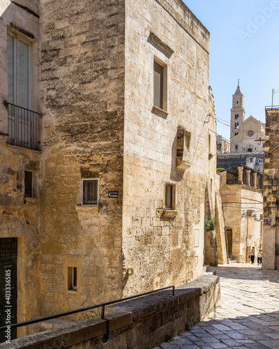 Fototapeta Naklejka Na Ścianę i Meble -  Scenic street in Sassi of Matera historic district leading with Matera Cathedral in the background, Italy