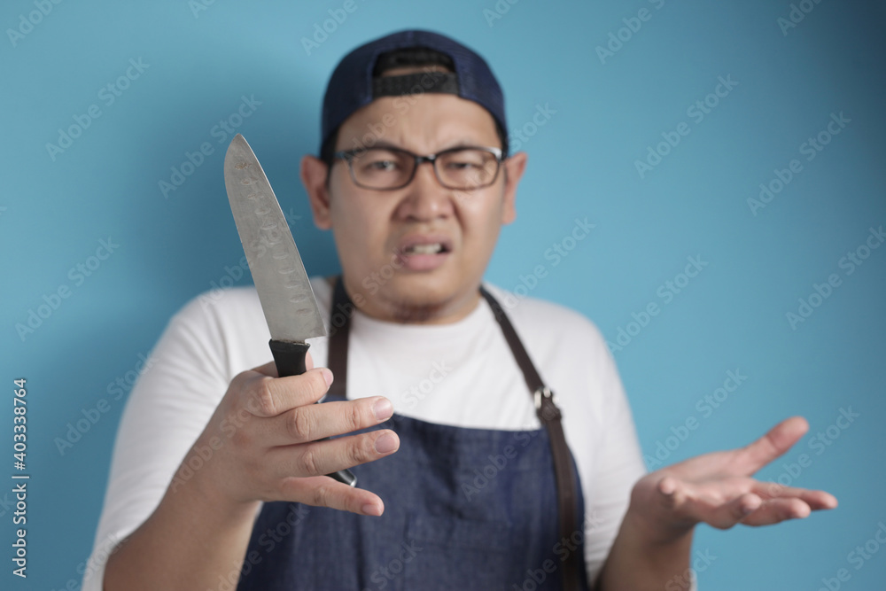 Portrait of Asian male chef confused while holding knife, don't know how to cook Portrait of Asian male chef confused while holding knife, don't know how to cook