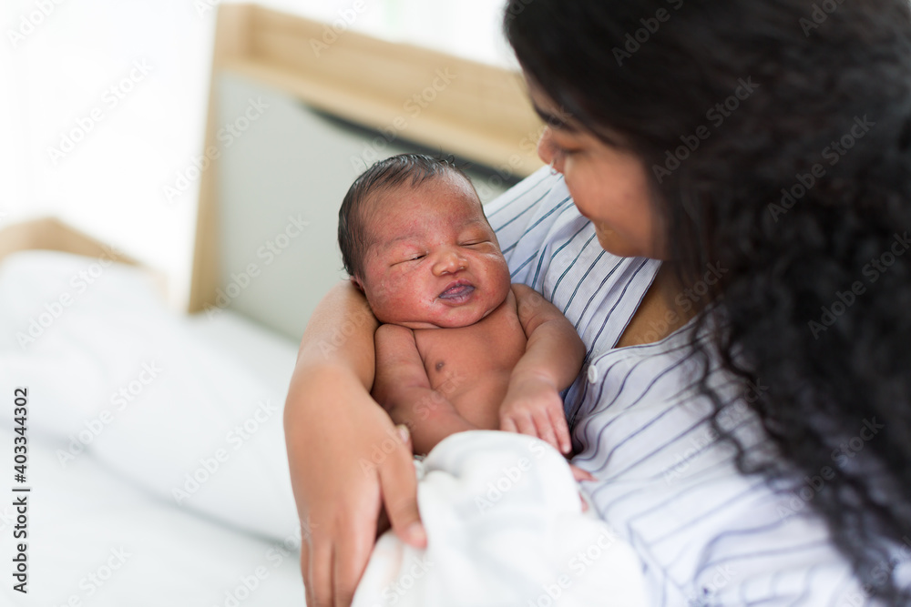 Happy African American mother holding her newborn baby on her arms. Infant lying on mother’ arms Happy African American mother holding her newborn baby on her arms. Infant lying on mother’ arms