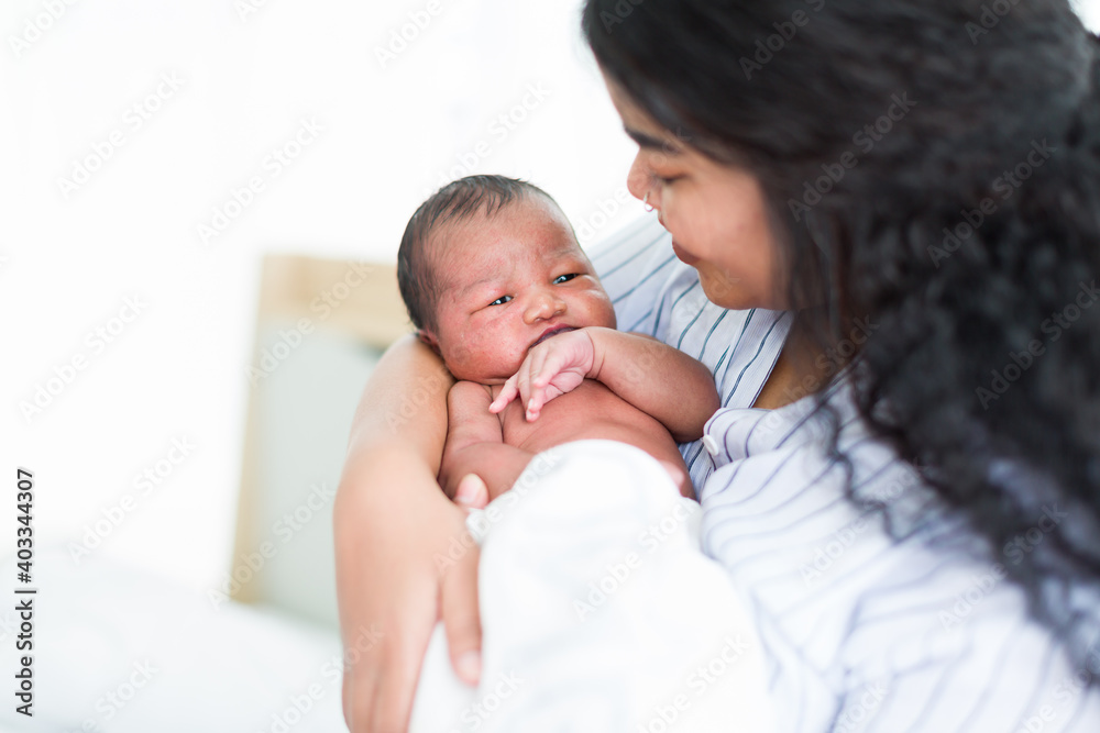 Happy African American mother holding her newborn baby on her arms. Infant lying on mother’ arms Happy African American mother holding her newborn baby on her arms. Infant lying on mother’ arms