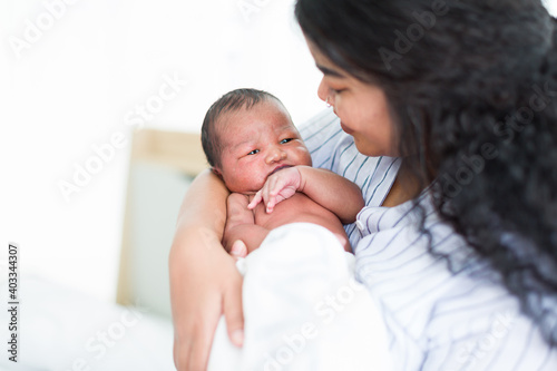 Happy African American mother holding her newborn baby on her arms. Infant lying on mother’ arms