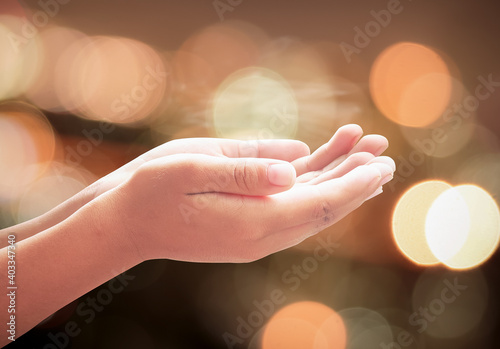 Children hands praying over abstract blurred spiritual light background