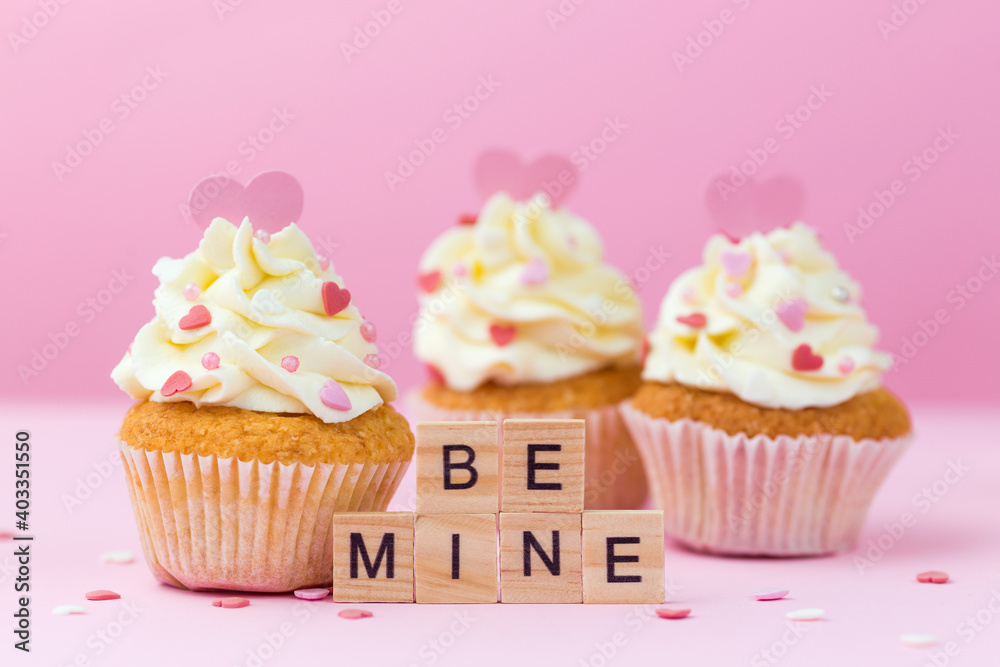 Valentine's day card. Be mine. Cupcakes decorated hearts on a pink background