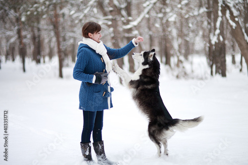 Girl walks with dog siberian husky in winter snowy forest