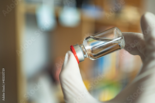 A vaccine bottle in a hand with glove