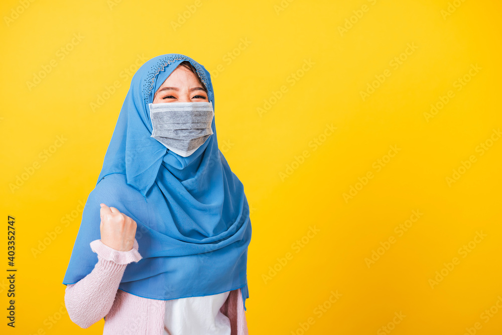 Asian Muslim Arab, Portrait of happy beautiful young woman Islam wear veil hijab and face mask protect raise hands glad excited cheerful after recovering from illness coronavirus isolated yellow Asian Muslim Arab, Portrait of happy beautiful young woman Islam wear veil hijab and face mask protect raise hands glad excited cheerful after recovering from illness coronavirus isolated yellow