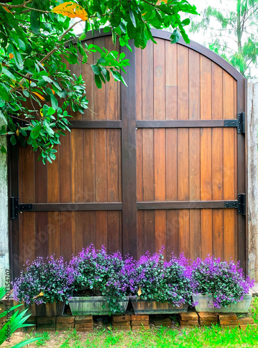 Wooden door swing on a large black steel frame in the garden. Ideas for Home Design and Decoration.