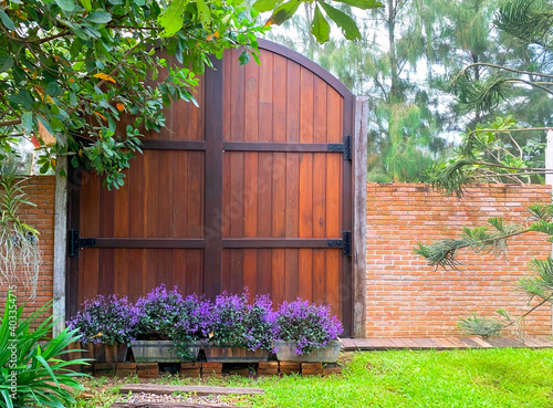 Wooden door swing on a large black steel frame in the garden. Ideas for Home Design and Decoration.