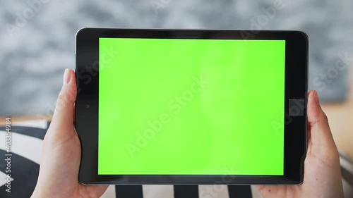 Close up of woman holding in hands a digital tablet with green screen for internet online, chromakey screen for advertising.