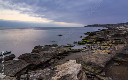 Cloudy sunrise on rocky sea coast, long exposure © Vastram