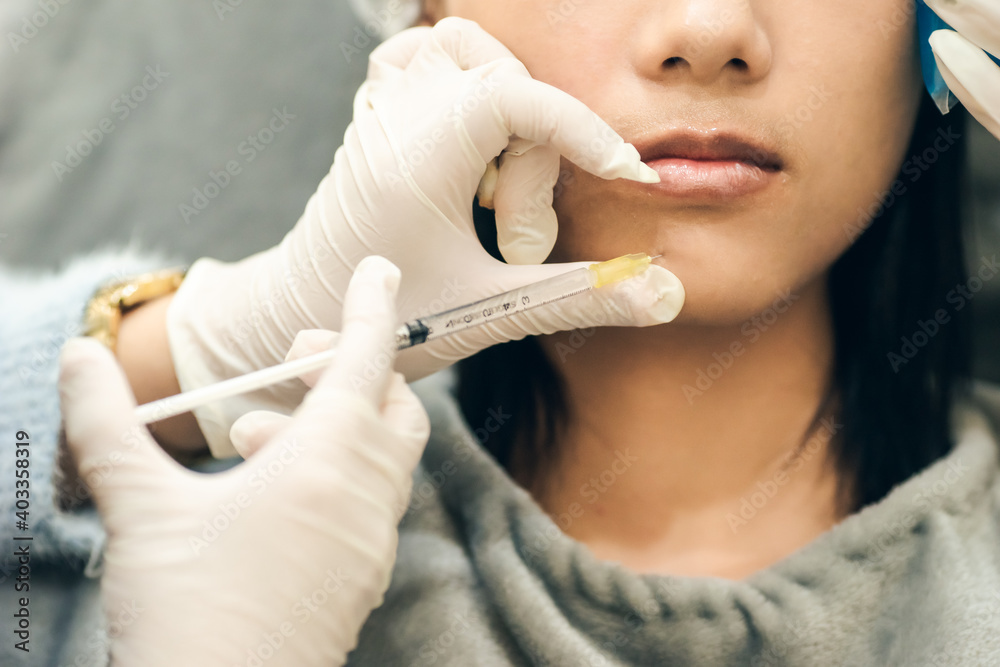 Closeup hand holding syringe injection to chin. Doctor cosmetologist ...