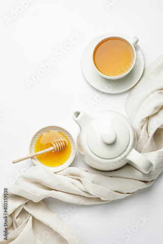 Composition with teapot, cup of tea and honey on white background