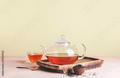 Glass teapot and cup of tea on table