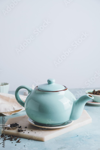 Teapot and dry tea leaves on table