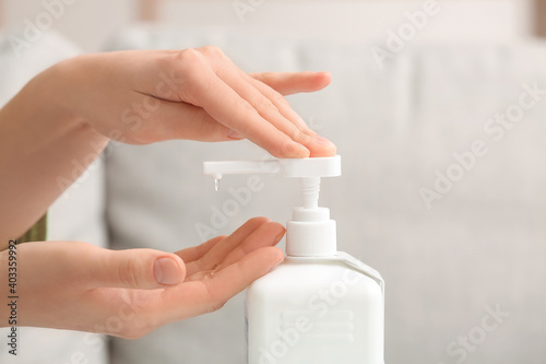 Young woman using sanitizer at home  closeup