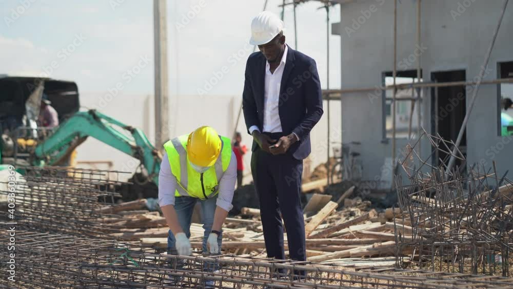 asian foreman and african american architect  checking steel structure outdoors on construction site at village . contractor worker Inspection and correction rebar steel cage . quality control