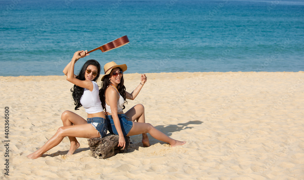Two happy women are sitting on the beach While relaxing on vacation for the weekend on sunny days and nice weather in travel and holiday concept.