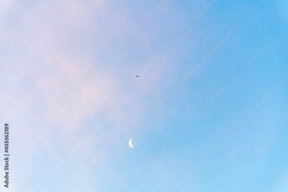 Beautiful blue sky with a partial moon showing on a bright, sunny day with few clouds that have a pink tinge on a crisp winter day. Beautiful blue sky with a partial moon showing on a bright, sunny day with few clouds that have a pink tinge on a crisp winter day.