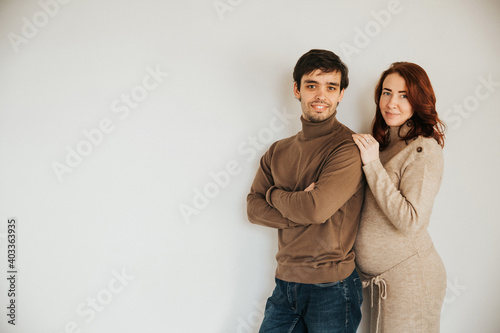portrait of a happy couple, husband and pregnant wife on a light background. A man and a woman are near.