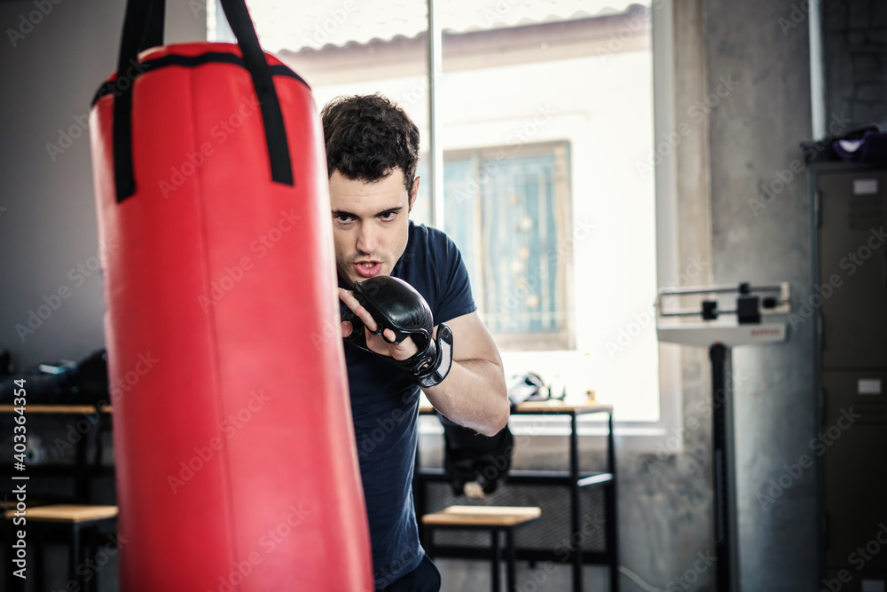Handsome man in boxing gloves punching bags exercise in fitness gym