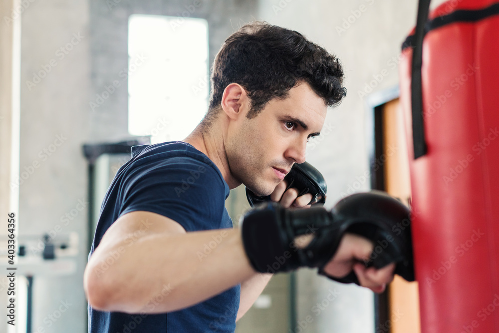 Handsome man in boxing gloves punching bags exercise in fitness gym