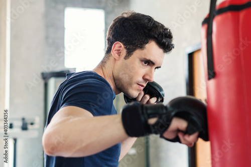 Handsome man in boxing gloves punching bags exercise in fitness gym © CasanoWa Stutio