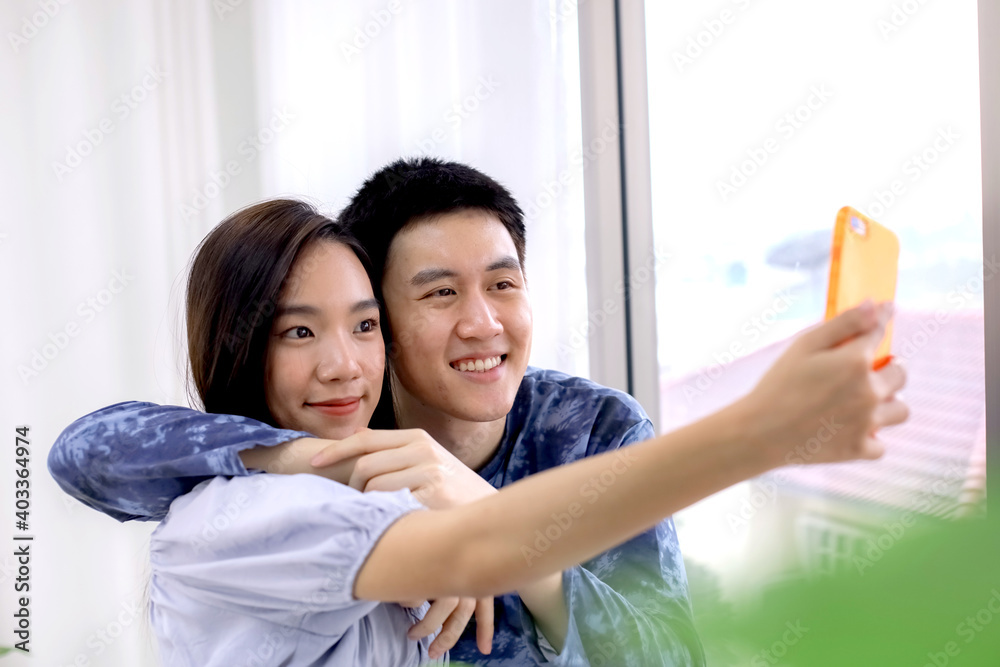 Asian couple making a selfie at hotel room by smartphone. Asian couples taking selfies at resort room. Journey, Travel concept. Honeymoon trip