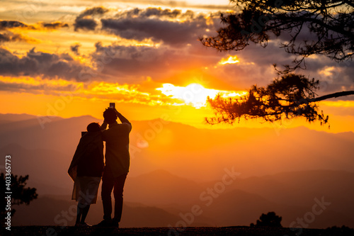 Couple photograph mountain view with sunset sky.