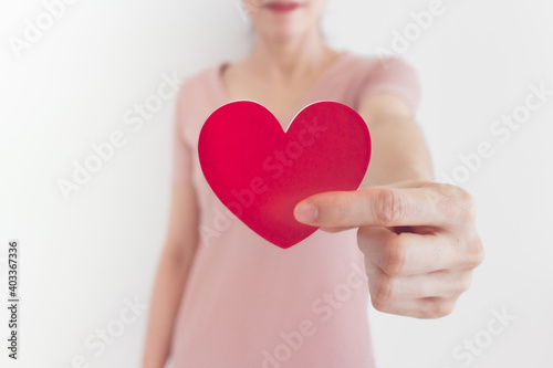 Woman in pink dress shows heart shape in the concept of love and valentine.