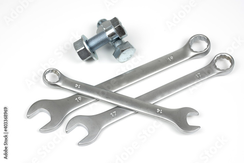 several metal bolts and nuts with wrenches on a white background